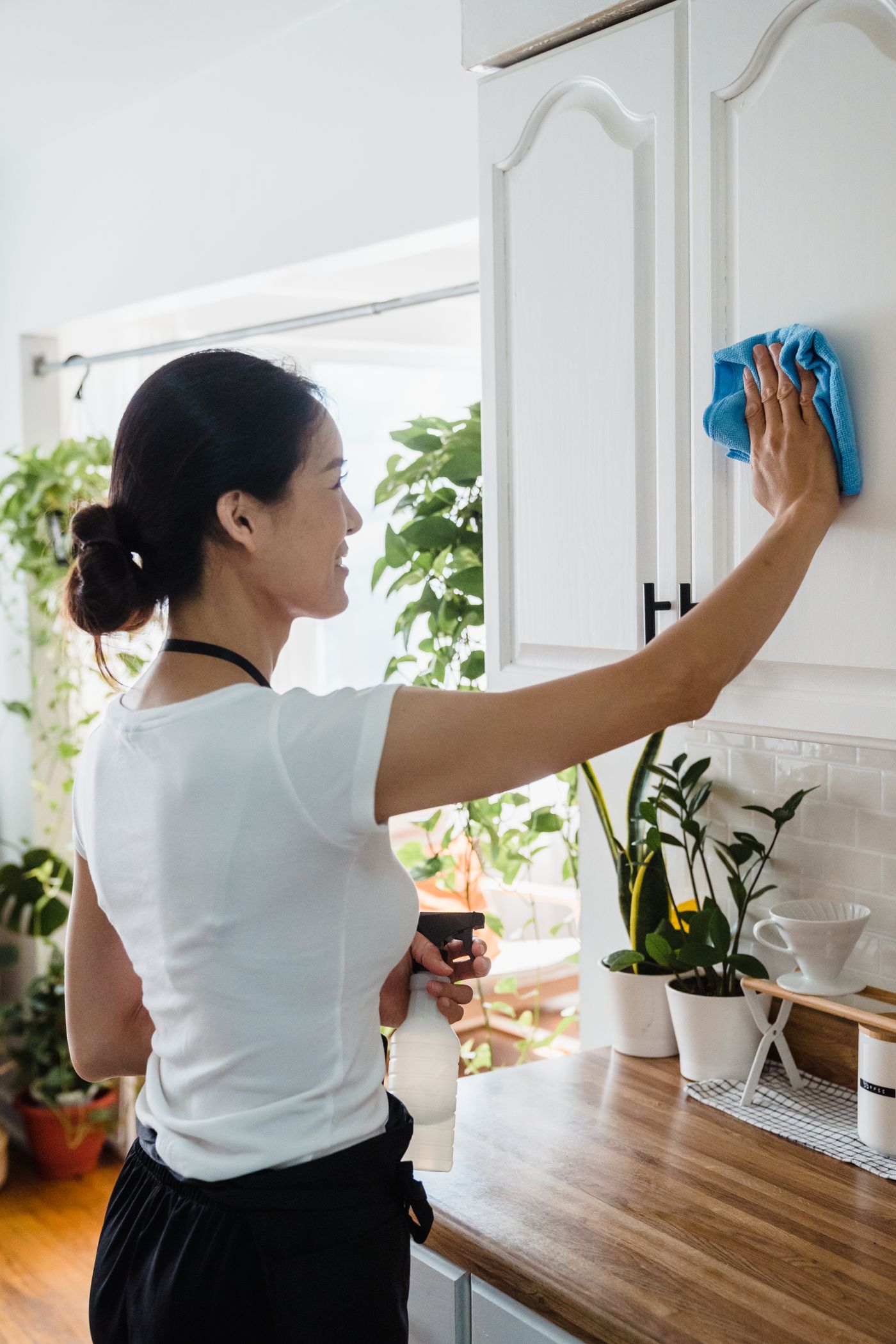 Cleaner wiping the face of a kitchen cabinet with a microfiber cloth